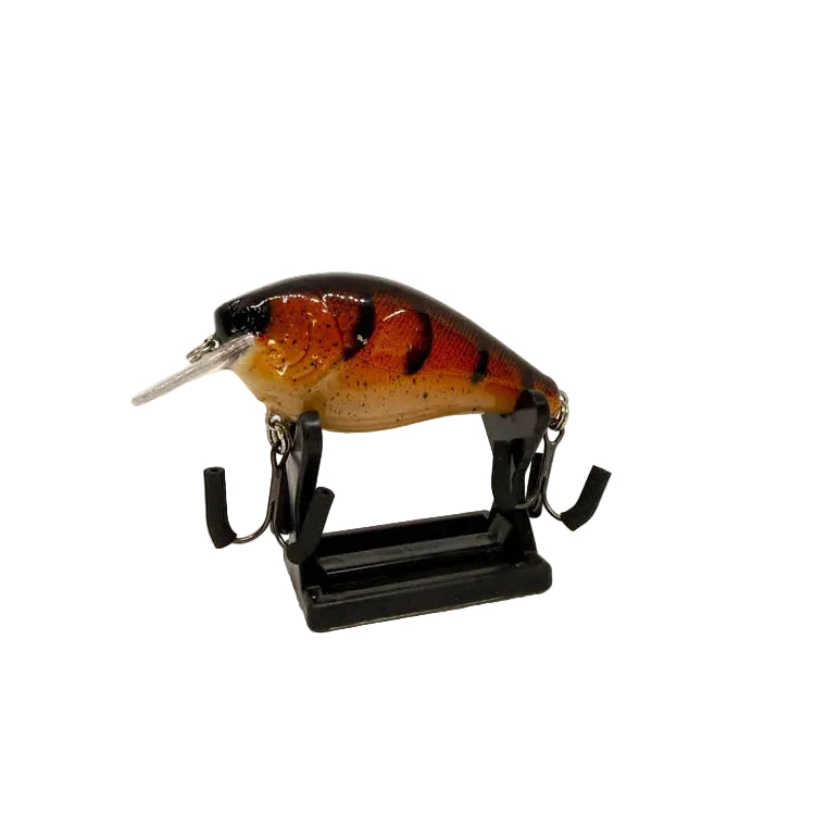 A hard bait fishing lure with a realistic fish design, featuring a black top, orange and brown speckled body, and a silver metal lip, displayed on a black stand against a white background.